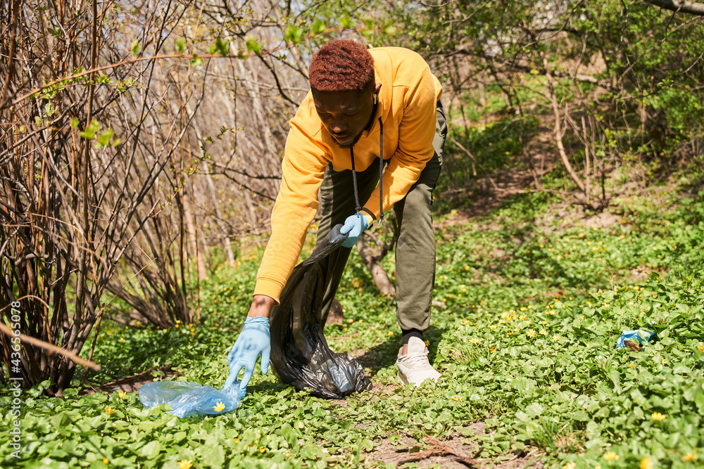 Multiracial volunteer helping to pick up waste by garbage bags Multiracial volunteer helping to pick up waste by garbage bags