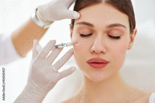 Cosmetician applying filler injection to patient