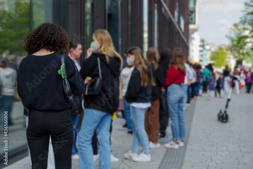 Selective focus view, Group of European women with protective face mask queue and wait for shopping on sidewalk outside store during lockdown by epidemic of COVID-19 in Düsseldorf, Germany.