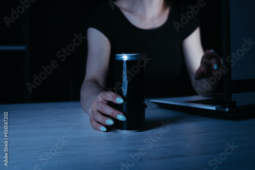 Focused woman drinking energy drink at night