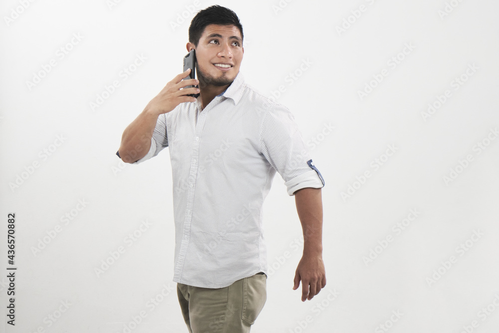 Hombre latino alegre habla por celular mientras mira hacia atrás Hombre latino alegre habla por celular mientras mira hacia atrás