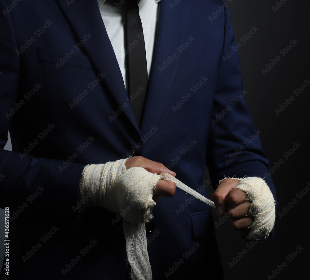 Closeup male hand of businessman fighter in suit with bandages and clenched fists.