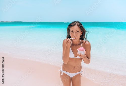 Ice cream dessert on beach. Happy Asian woman eating delicious frozen fruit yogurt or Acai smoothie bowl healthy food on Caribbean beach vacation travel.