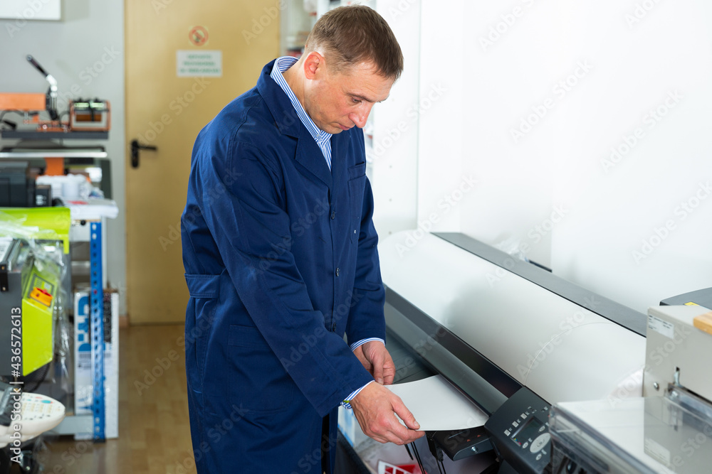 Service man uses plotter in printing shop. High quality photo