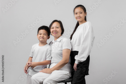 Portrait of Grandmother and grandchild hugging, looking at camera and smiling, on gray background