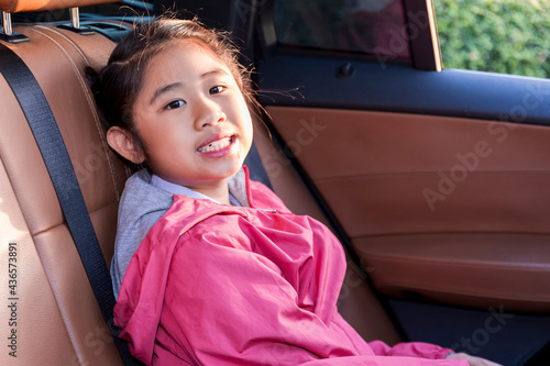 Asian Happy student smiling with camera while enjoying road trip in car. Daughter smiling and looking camera inside car in morning. Asian cildrens sitting in car on the way go to school. Family in car photo