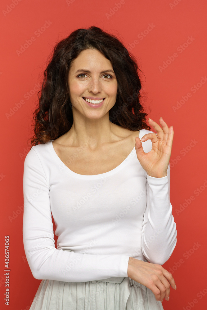 Portrait of happy smiling young woman show ok sign. Cheerful satisfied client or customer say okay to service, product. Isolated on red pleased curly millennial female demonstrate positive evaluation Portrait of happy smiling young woman show ok sign. Cheerful satisfied client or customer say okay to service, product. Isolated on red pleased curly millennial female demonstrate positive evaluation
