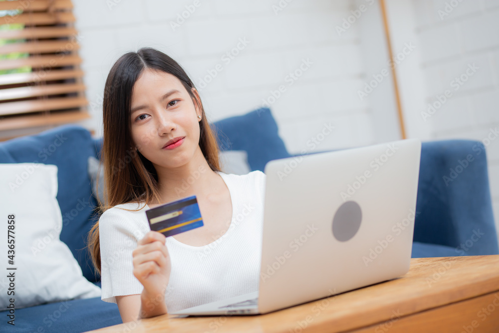 Young asian woman sit on sofa using laptop computer shopping online with credit card buying to internet, happy girl payment with e-business on couch, purchase and payment, business concept. Young asian woman sit on sofa using laptop computer shopping online with credit card buying to internet, happy girl payment with e-business on couch, purchase and payment, business concept.