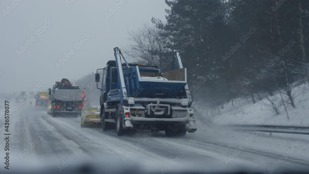 POV from a car driving behind a snowplow during a heavy snow blizzard.
