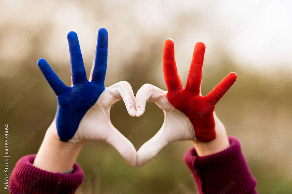 custom made wallpaper toronto digitalLove and happiness concept. Cute child forming heart gesture with hands outdoors on nature sunset bokeh background. Heart shape of kids hand painted in france flag colors, kids body language