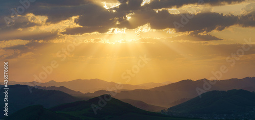 Picturesque sunrise in the mountains, sun rays