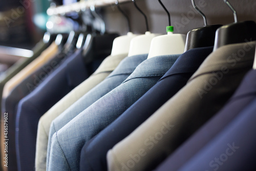 Assortment of suit jackets on hanger racks in menswear clothing store for selling