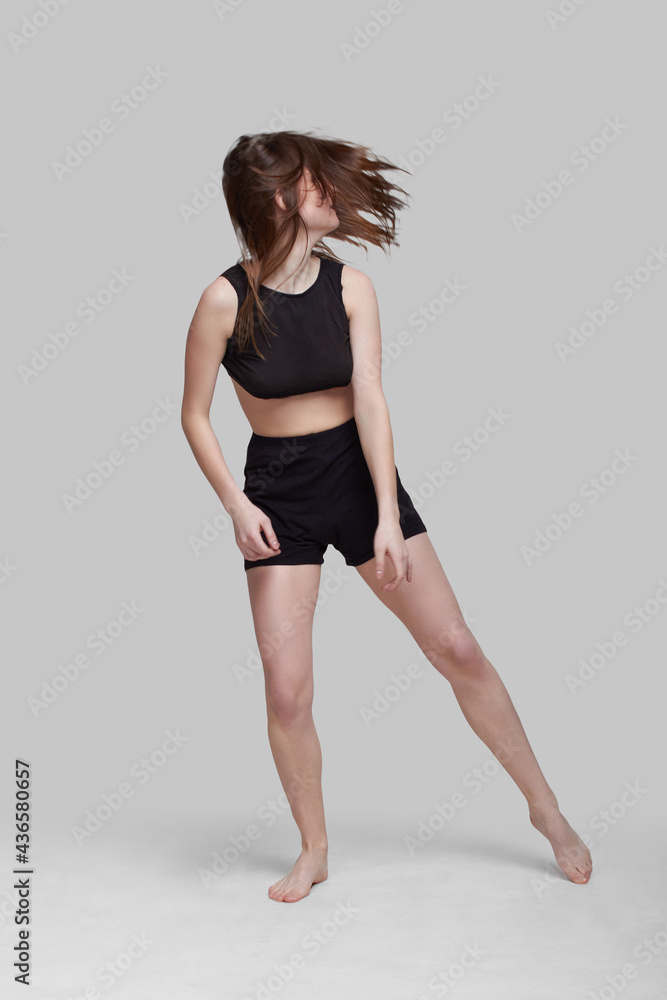 Young slim athletic girl, with long hair, in a black top and shorts, dancing in the white studio. motion blur Young slim athletic girl, with long hair, in a black top and shorts, dancing in the white studio. motion blur