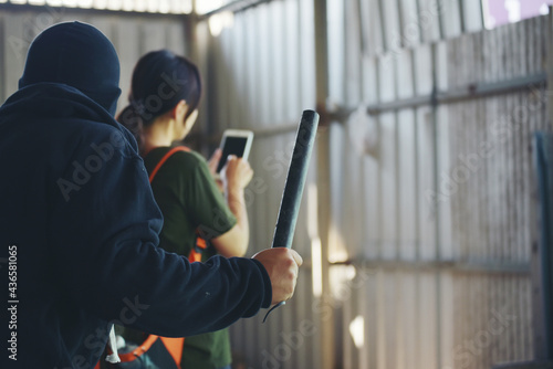 Thief armed man rob woman by baton on street stalker behind young woman back. Woman on phone careless stalker sneaking to steal, rob aggressive by danger bandit. Thief using baton nightstick weapon.