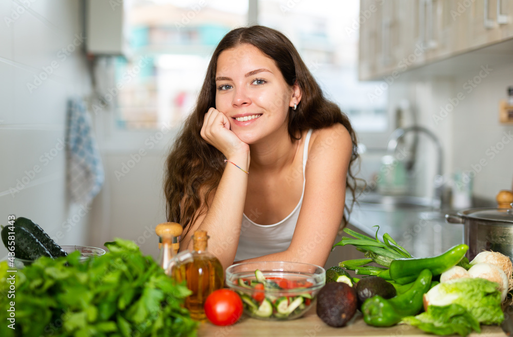 Emotional young brunette woman posing on camera at kitchen
