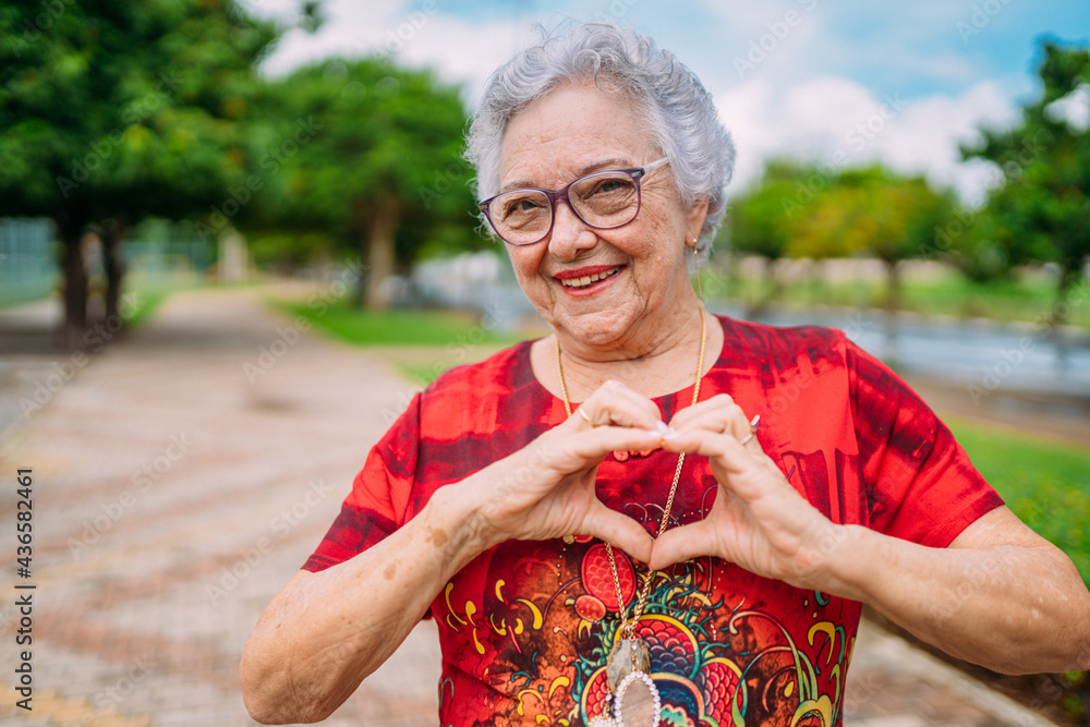 Joyful senior lady in glasses laughing heart with hands. Latin American woman. Brazilian elderly woman. - obrazy, fototapety, plakaty 