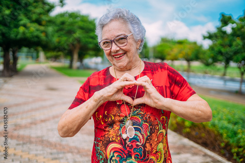 Bild auf Leinwand Joyful senior lady in glasses laughing heart with hands
