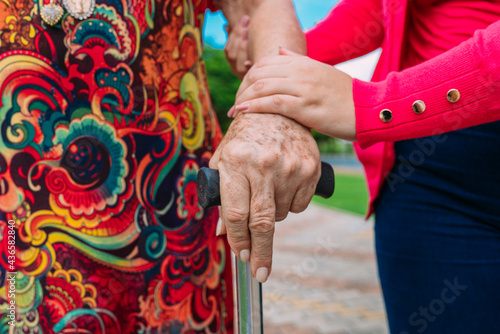 The helping hands for walking stick elderly woman home care in a park outdoor.