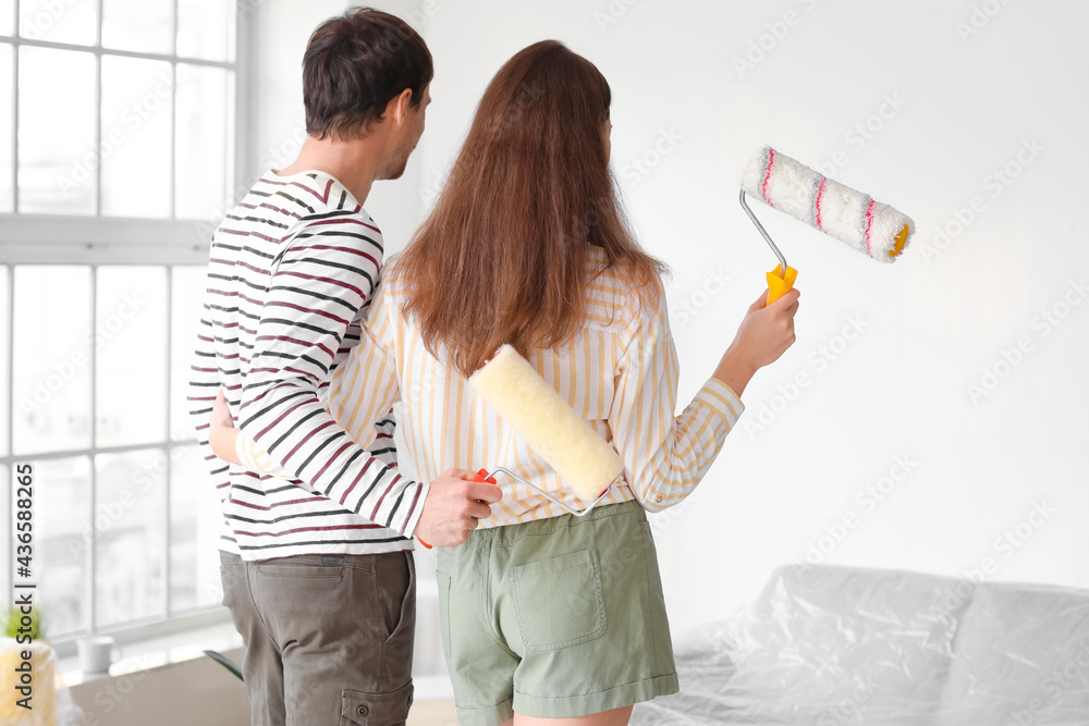 Happy couple with paint rollers planning design of their new house