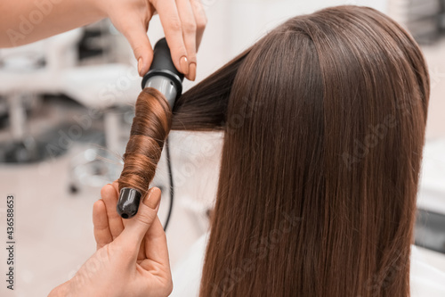 Canvas Print Female hairdresser curling hair of client in beauty salon, closeup