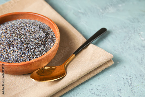 Plate and spoon with poppy seeds on color background