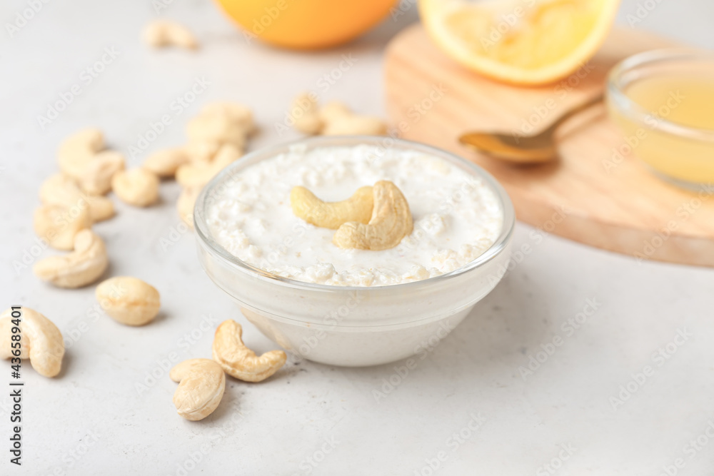 Bowl with cashew sour cream, nuts and lemon juice on light background, closeup Bowl with cashew sour cream, nuts and lemon juice on light background, closeup
