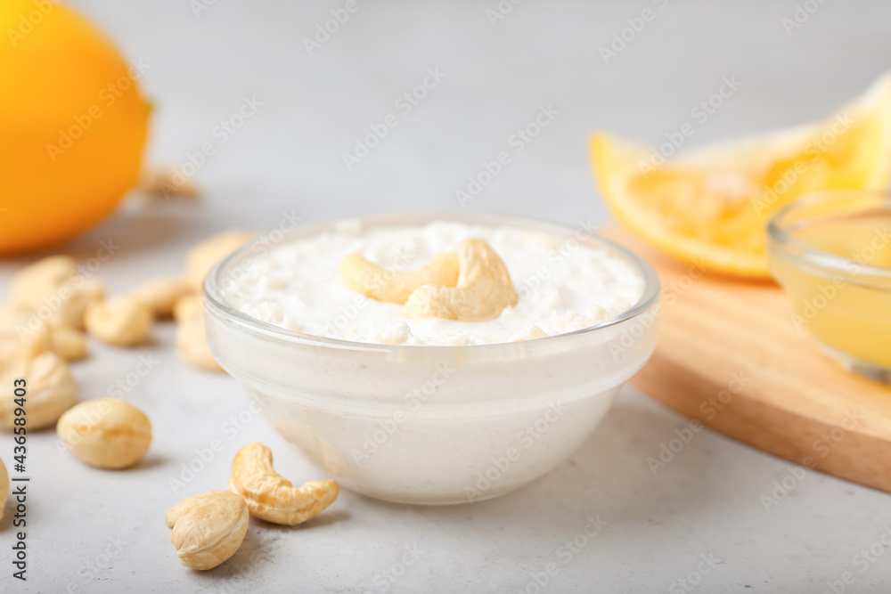 Bowl with cashew sour cream, nuts and lemon juice on light background, closeup Bowl with cashew sour cream, nuts and lemon juice on light background, closeup