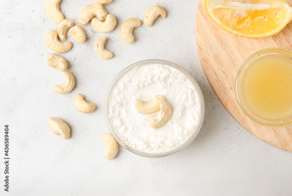 Bowl with cashew sour cream, nuts and lemon juice on light background Bowl with cashew sour cream, nuts and lemon juice on light background
