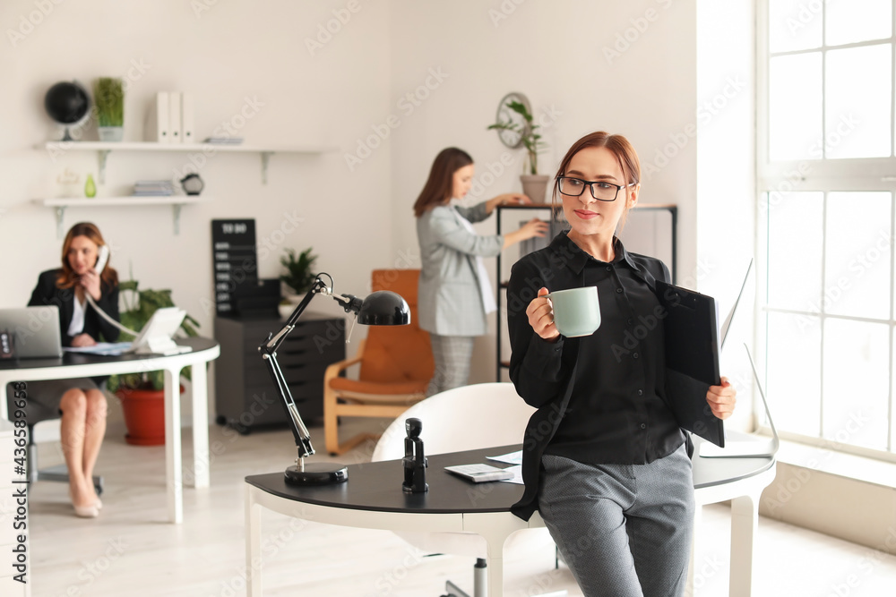 Female accountant with cup of coffee in office Female accountant with cup of coffee in office