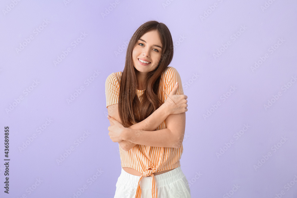Young woman hugging herself on color background