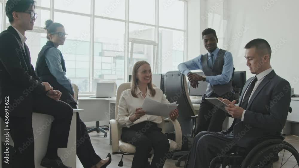 Medium shot of diverse team of colleagues in formal wear having casual meeting in office Medium shot of diverse team of colleagues in formal wear having casual meeting in office
