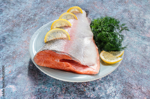 Fresh trout with lemon and dill on a grey plate on the kitchen table awaits cooking. Restaurant menu. Dietary product. Keto diet. The concept of healthy eating.