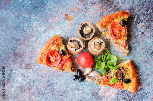 Three pieces of vegetarian homemade pizza lie on a blue background. Pizza with mushrooms, tomatoes, olives, Basil and garlic on a blue background. Top view. Copy space.