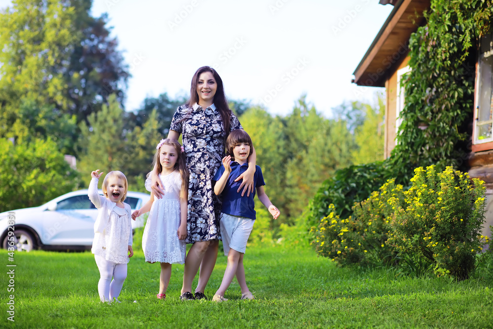 Obraz premium Young large family on a summer morning walk. Beautiful mother with children is playing in the park.
