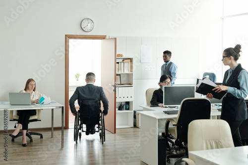 Businessman in wheelchair moving towards his office in working environment