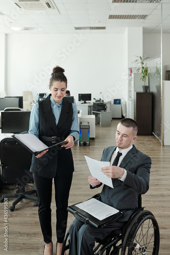 Disabled boss and his secretary discussing new contract in large office