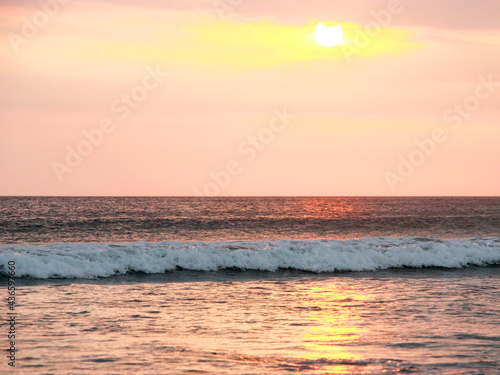 The picturesque sunset at the sea on the island Bali. The golden and pink colour of the ocean background.