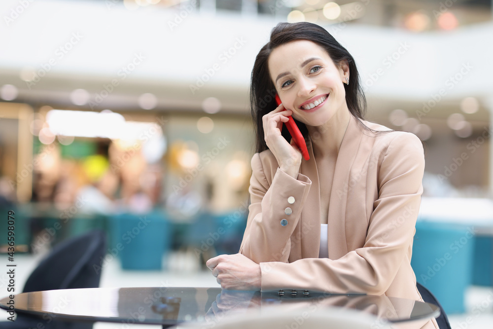 Smiling woman talking on smartphone while sitting in coffee