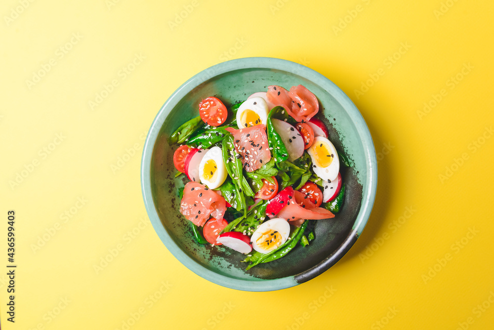 Salad with spinach, eggs and radish in a bowl over bright yellow background. Salad with spinach, eggs and radish in a bowl over bright yellow background.