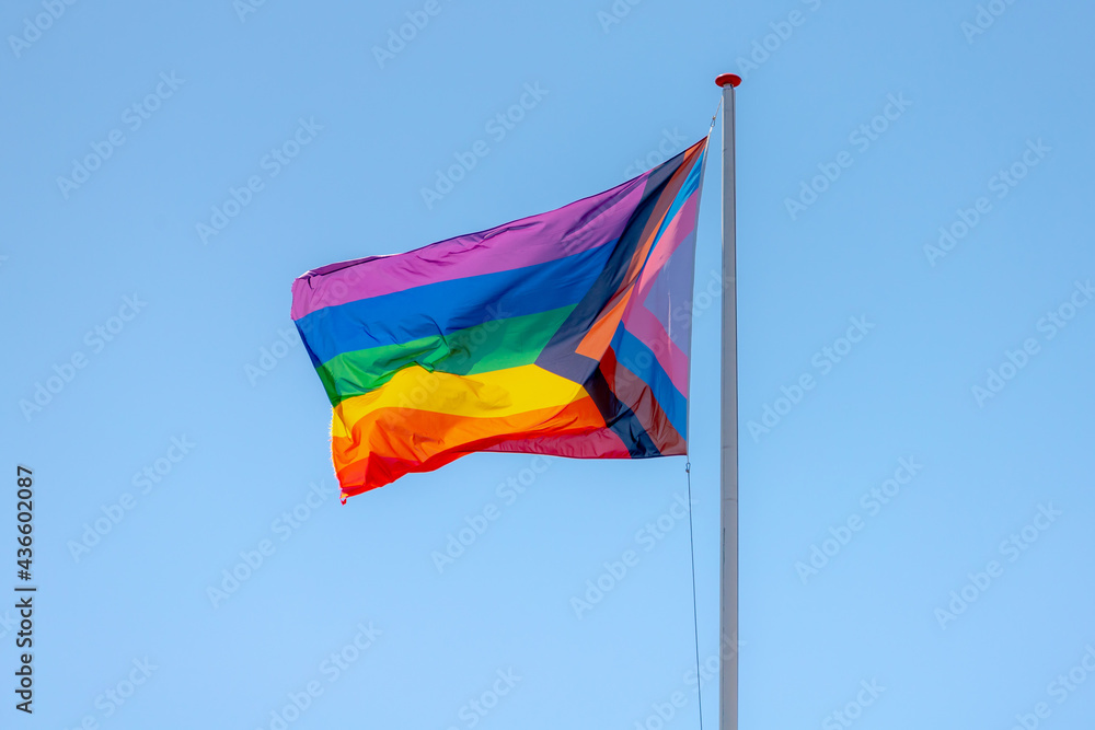 Progress pride flag (new design of rainbow flag) waving in the air with blue sky, Celebration of gay pride, The symbol of lesbian, gay, bisexual and transgender, LGBTQ community around the world. Progress pride flag (new design of rainbow flag) waving in the air with blue sky, Celebration of gay pride, The symbol of lesbian, gay, bisexual and transgender, LGBTQ community around the world.