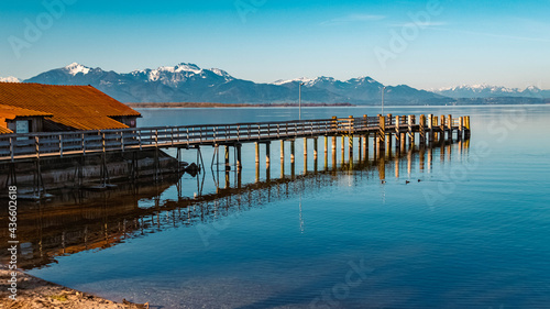 Beautiful alpine spring morning view with reflections, details of a pier and the alps in the background at the famous Chiemsee, Chieming, Chiemgau, Bavaria, Germany