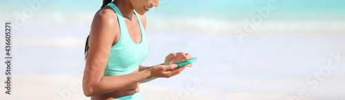 Fitness online app fit active girl using mobile phone for heatlh and exercise tracking progress on tech device. Panoramic banner of athlete woman monitoring her sport.