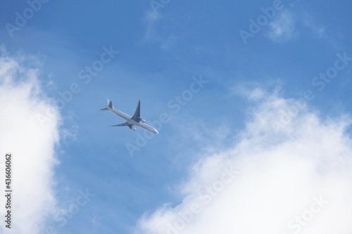 Airplane flying in blue sky on background of white clouds. Two-engine commercial plane, turbulence and travel concept