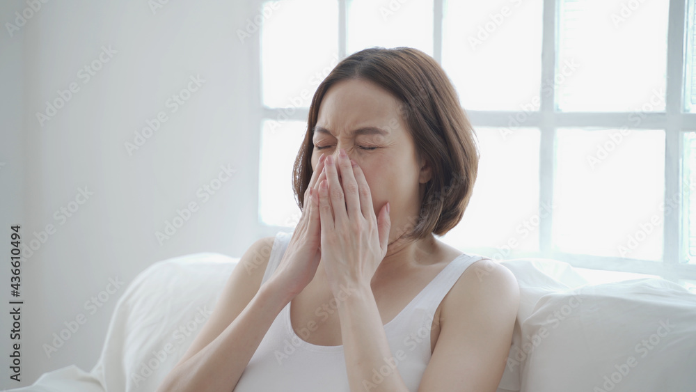 asian woman in white allergy and sneezing on sofa in living room day time. Irritated nose sneeze. authentic lifestyle at home. asian woman in white allergy and sneezing on sofa in living room day time. Irritated nose sneeze. authentic lifestyle at home.