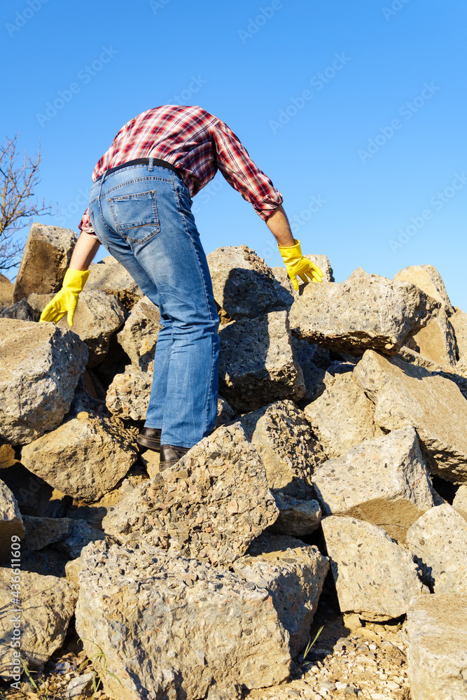 a man works with a pile of stones and broken pieces of concrete, carries construction debris a man works with a pile of stones and broken pieces of concrete, carries construction debris