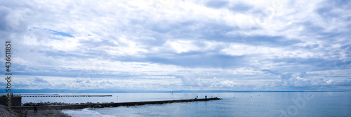 pier with fishermen, in the background the sea and a cloudy sky. banner © Luca