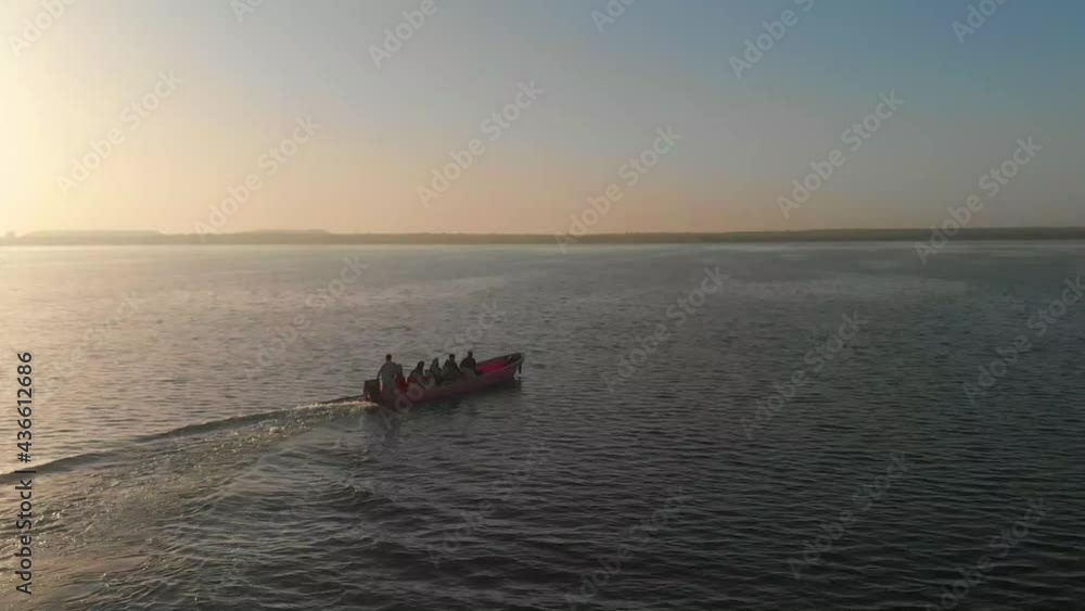 Speedboat With People On Board Moving Across Keenjhar Lake In Thatta During Golding Hour. Aerial View Speedboat With People On Board Moving Across Keenjhar Lake In Thatta During Golding Hour. Aerial View