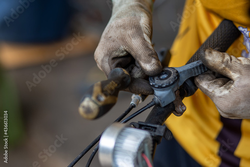 Bicycle gear Being removed for repair By a mechanic wearing white cloth gloves stained with oil on a mountain bike