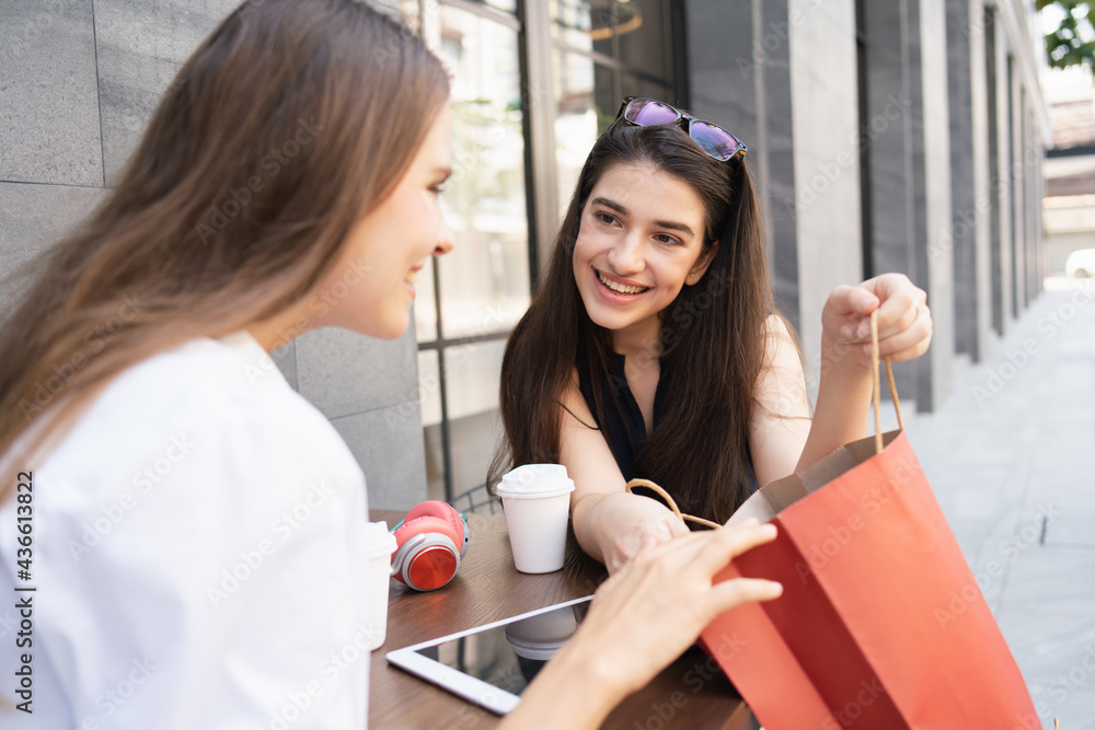 two woman having coffee break and looking something in the shopping bags two woman having coffee break and looking something in the shopping bags