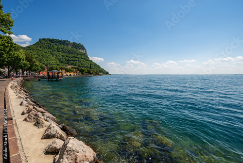 Coastline in front of the small town of Garda, tourist resort on the coast of Lake Garda (Lago di Garda). Beautiful bay with the hill called Rocca di Garda. Verona province, Veneto, Italy, Europe.